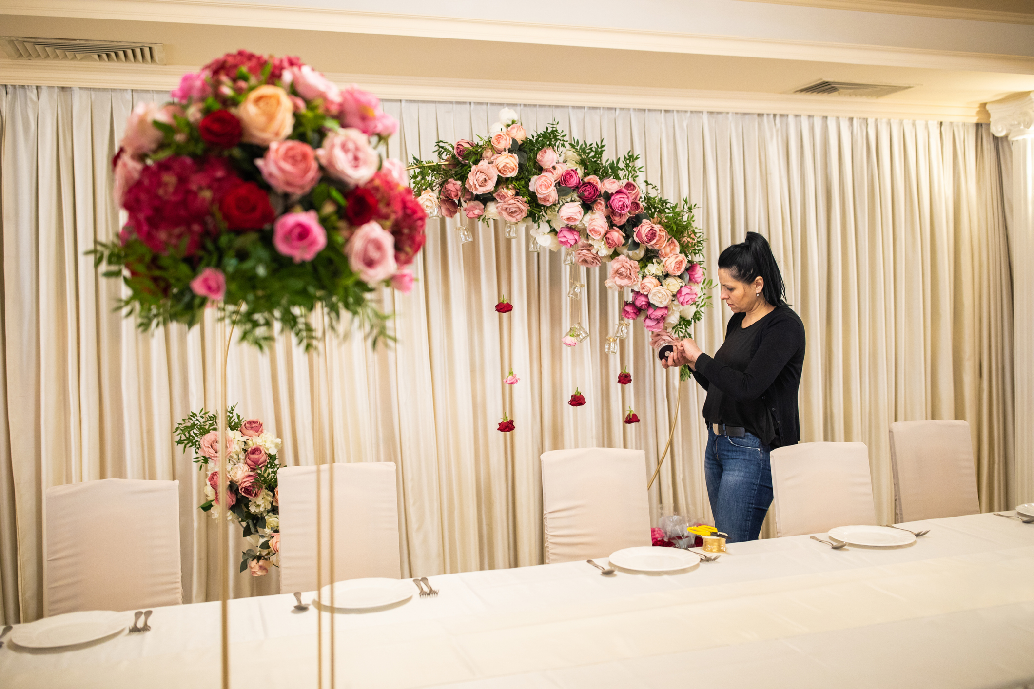 Woman arranging floral wedding decorations indoors.