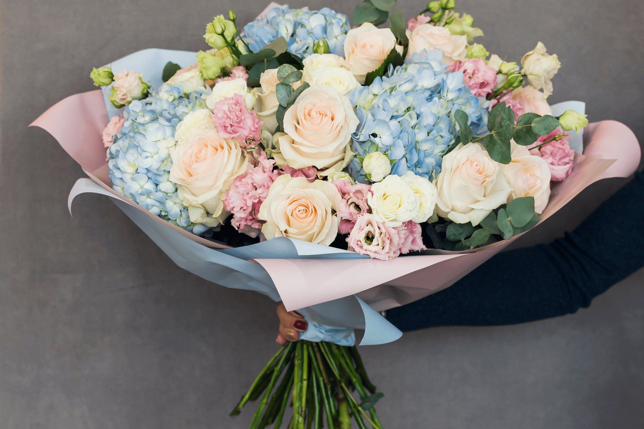 Bouquet of pastel roses and hydrangeas held.