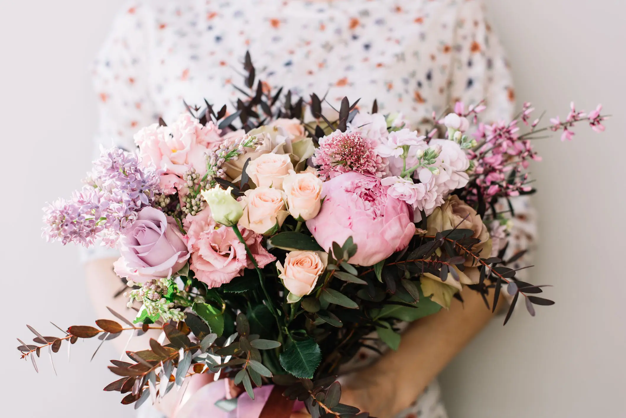 Person holding bouquet of pastel flowers.